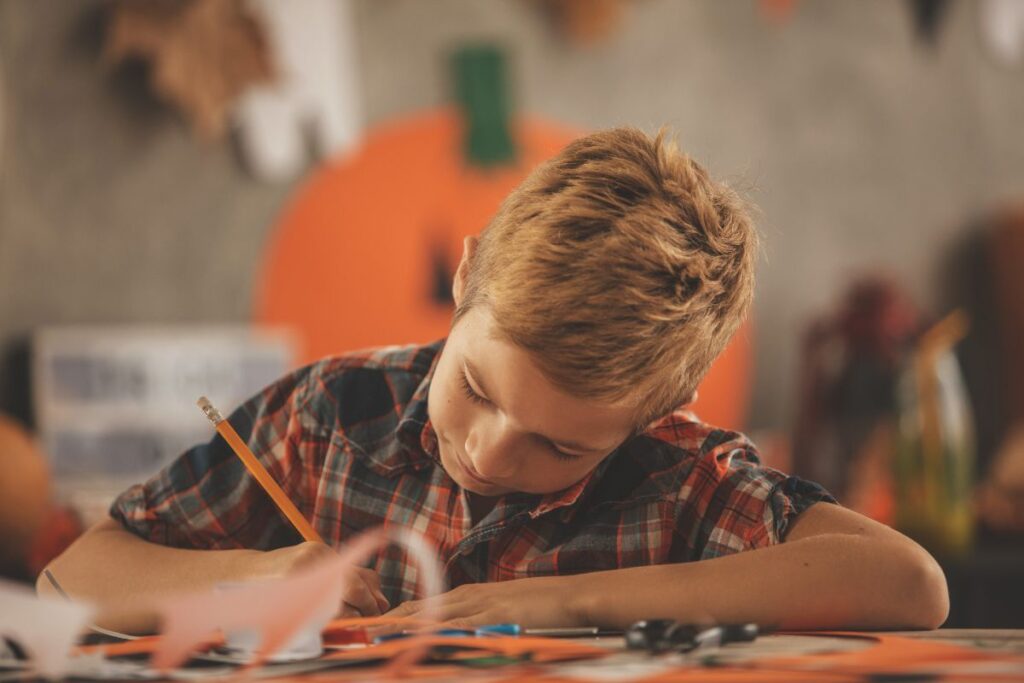 Un bambino con una matita che sta scrivendo a scuola. La scrittura creativa per i bambini è importante