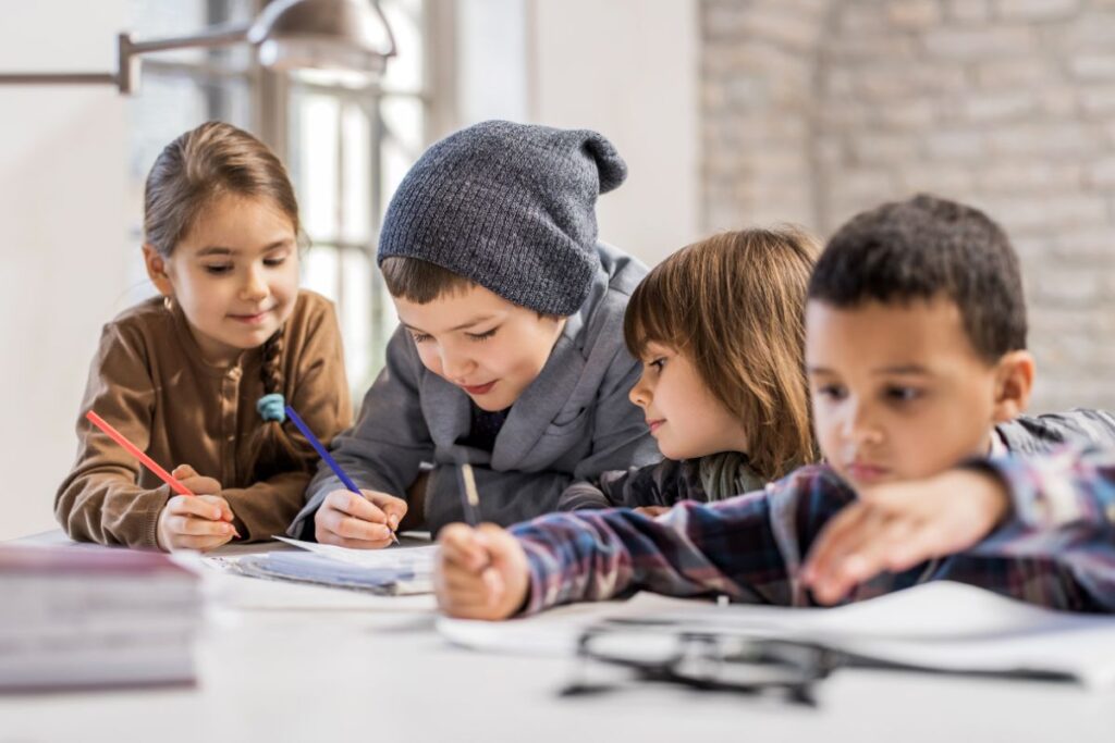 4 bambini a scuola si divertono scrivendo delle storie e disegnando.
La scrittura creativa per i bambini è importante