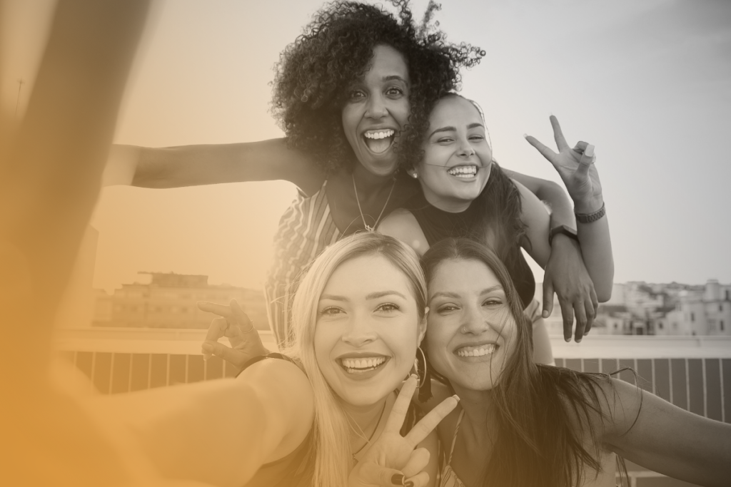 quattro ragazze di etnie diverse, si fanno un selfie sorridendo. Sono felici e bellissime