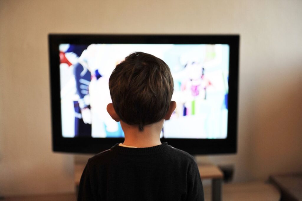 Un bambino che guarda la televisione per molto tempo. L'eccessiva esposizione alle luci può danneggiare la vista, la mente e il corpo del bambino.