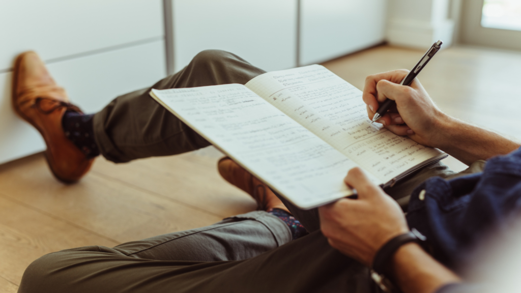 Un ragazzo scrive un diario nella sua stanza mentre è seduto per terra. Perché scrivere fa bene